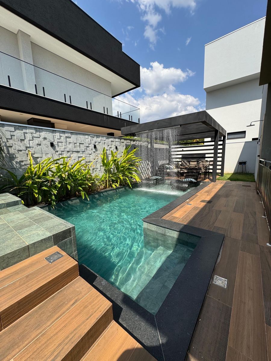 Piscina com cascata e deck de madeira - projeto Emporium Piscinas